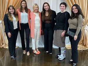 Society for Human Resource Management student chapter stand together in front of beige curtains